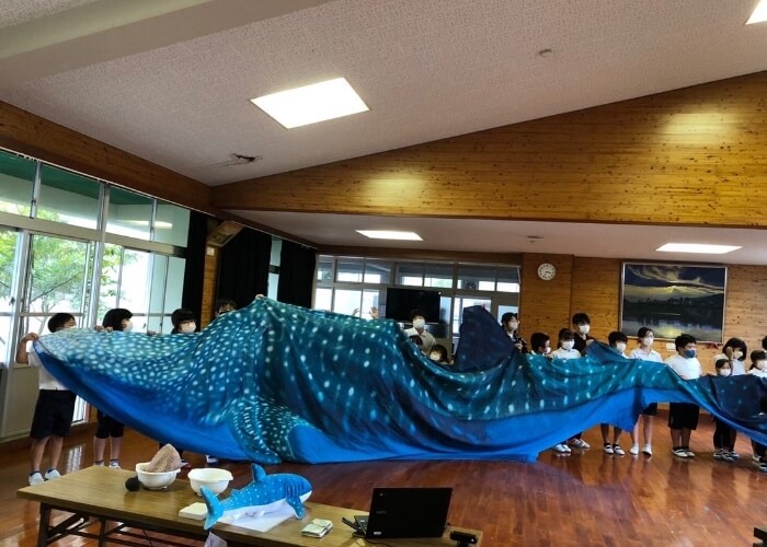実寸大のジンベイザメの布を持つ子供たち